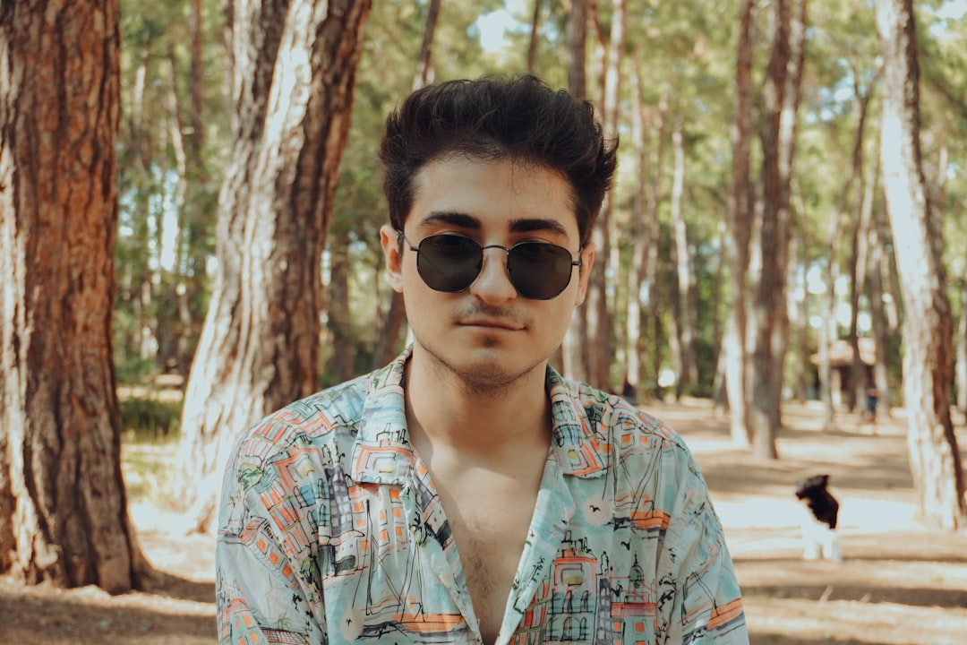 A man wearing sunglasses standing in a forest